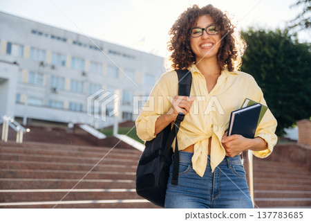 With backpack. Beautiful woman student is near the university outdoors With backpack. Beautiful woman student is near the university outdoors 137783685