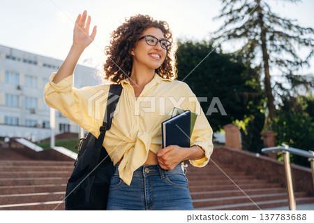 Hello hand gesture. Beautiful woman student is near the university outdoors 137783688