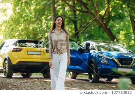 Posing for the camera. Young woman is in the forest with two cars Posing for the camera. Young woman is in the forest with two cars 137783983