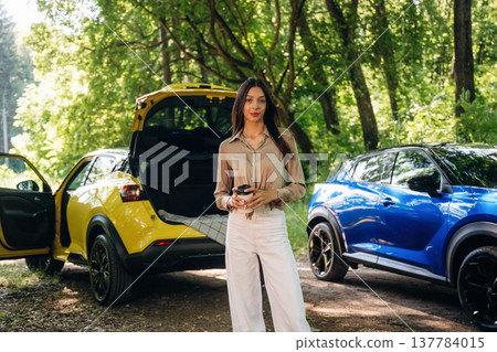Young woman is in the forest with two cars 137784015