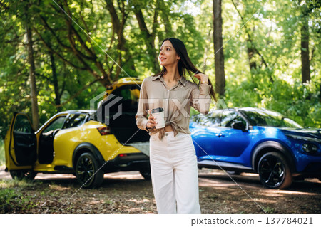 Young woman is in the forest with two cars Young woman is in the forest with two cars 137784021