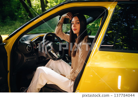 Relaxed, sitting, door is opened. Woman is with her car in the forest Relaxed, sitting, door is opened. Woman is with her car in the forest 137784044