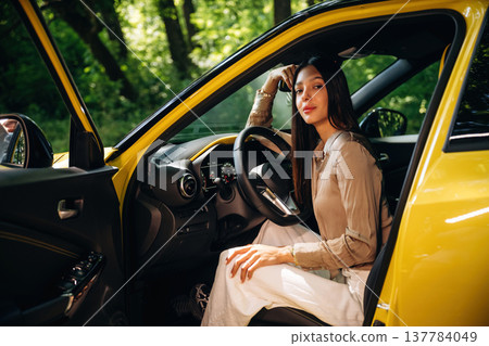 Side view, driver is sitting. Woman is with her car in the forest Side view, driver is sitting. Woman is with her car in the forest 137784049