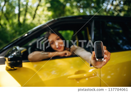 Happy owner is holding keys. Woman is with her car in the forest Happy owner is holding keys. Woman is with her car in the forest 137784061