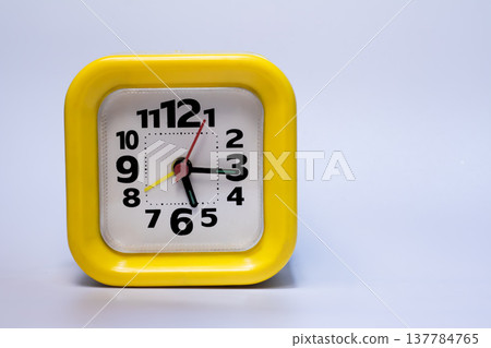 Bright yellow square alarm clock with black numbers isolated on white background. Time management, punctuality, deadline and schedule concept, studio shot with copy space. Bright yellow square alarm clock with black numbers isolated on white background. Time management, punctuality, deadline and schedule concept, studio shot with copy space. 137784765
