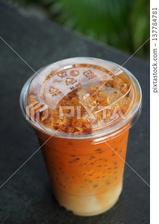 top view ice and cool orange and white thai tea in a plastic cup placed on a black table background, drink, ice, cool, object, fresh, copy space 137784781