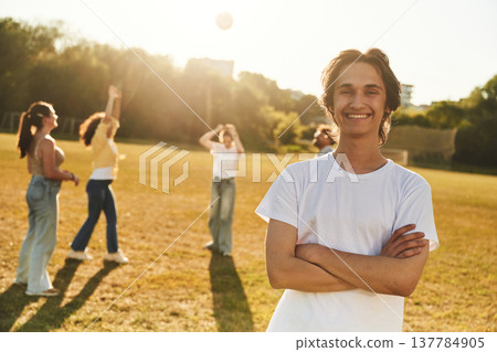 Guy is standing in front of other people. Young friends are having fun on the field 137784905