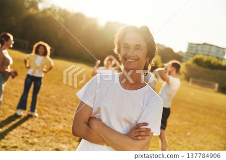 Guy is standing in front of other people. Young friends are having fun on the field 137784906