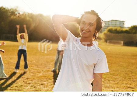Guy is standing in front of other people. Young friends are having fun on the field Guy is standing in front of other people. Young friends are having fun on the field 137784907