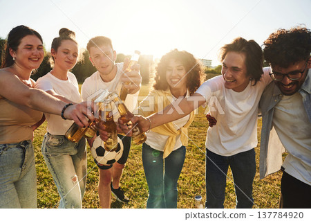 Quality drink, holding beer bottles and cheering. Young friends are having fun on the field 137784920
