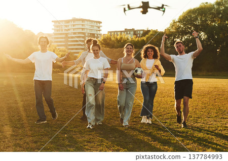 Drone is flying. Young friends are having fun on the field with soccer ball Drone is flying. Young friends are having fun on the field with soccer ball 137784993