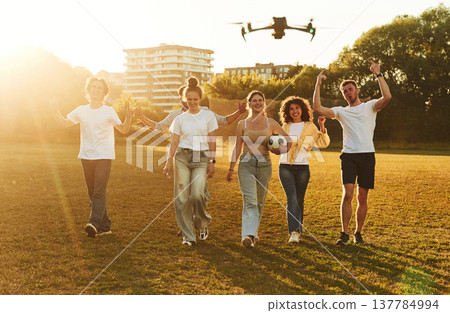 Drone is flying. Young friends are having fun on the field with soccer ball Drone is flying. Young friends are having fun on the field with soccer ball 137784994