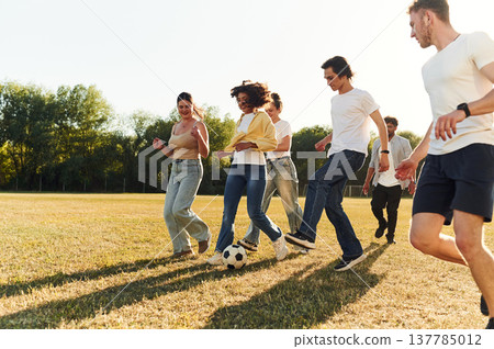 Summertime fun. Group of friends are playing soccer on the field Summertime fun. Group of friends are playing soccer on the field 137785012