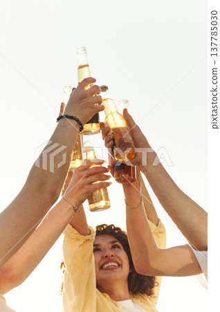 Close up view of friends that are cheering with bottles of beer outdoors 137785030