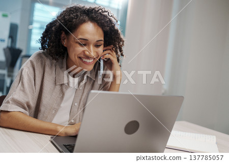 Woman Chats Animatedly At Desk. Laughter And Conversation Spark Creativity At Shared Workspace Table Woman Chats Animatedly At Desk. Laughter And Conversation Spark Creativity At Shared Workspace Table 137785057