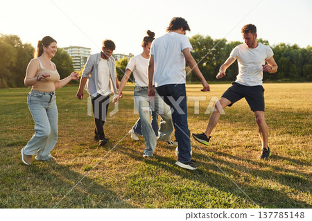 Males and females. Young friends are having fun on the field with soccer ball 137785148