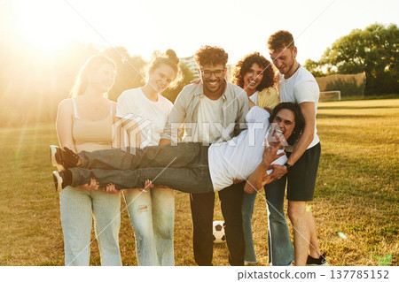 Positive facial expressions. Young friends are having fun on the field with soccer ball 137785152