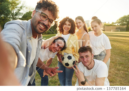 Males and females. Young friends are having fun on the field with soccer ball 137785164