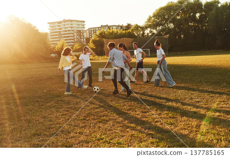 Males and females. Young friends are having fun on the field with soccer ball 137785165