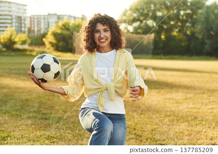 About to throw the soccer ball. Happy young woman is standing on the field About to throw the soccer ball. Happy young woman is standing on the field 137785209