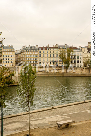 Parisian cityscape featuring historic buildings lining the Seine River embankment on an overcast sky day in Paris, France Parisian cityscape featuring historic buildings lining the Seine River embankment on an overcast sky day in Paris, France 137785270