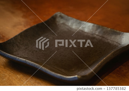 Black square plate for Japanese food, wooden table background Black square plate for Japanese food, wooden table background 137785382