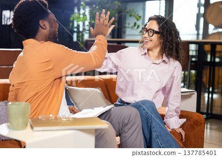 Happy colleagues giving high five during celebration standing Happy colleagues giving high five during celebration standing 137785401
