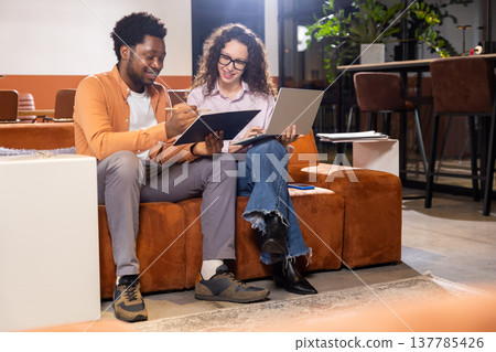Happy woman and man with laptop and tablet working together in office Happy woman and man with laptop and tablet working together in office 137785426