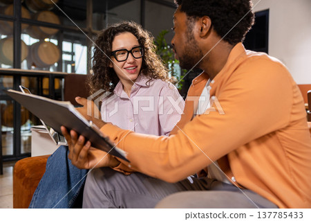 Smiling coworkers holding laptop and tablet collaborating Smiling coworkers holding laptop and tablet collaborating 137785433