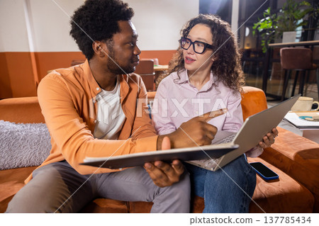Wavy haired woman and man with laptop and tablet working together Wavy haired woman and man with laptop and tablet working together 137785434