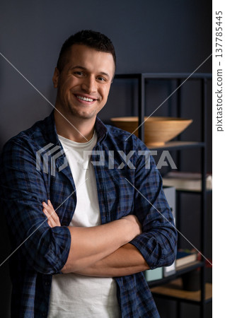 Confident male standing arms crossed gazing away in modern office interior Confident male standing arms crossed gazing away in modern office interior 137785445