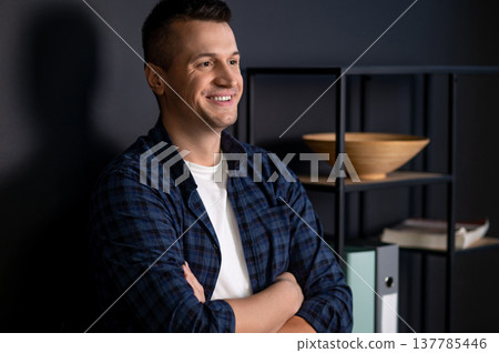 Confident man with crossed arms looking away standing in modern office interior 137785446