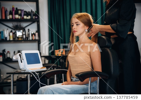Customer is sitting on the chair. Woman is in a beauty salon with hair stylist Customer is sitting on the chair. Woman is in a beauty salon with hair stylist 137785459