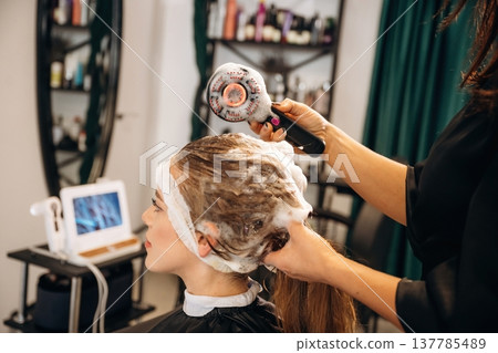 Woman is in a beauty salon with hair stylist Woman is in a beauty salon with hair stylist 137785489