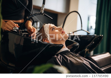 Lying down, washing the hair. Woman is in a beauty salon with hair stylist Lying down, washing the hair. Woman is in a beauty salon with hair stylist 137785490