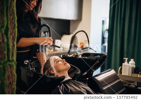 Lying down, washing the hair. Woman is in a beauty salon with hair stylist 137785492