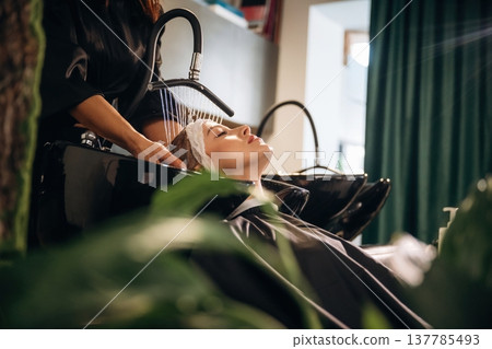 Lying down, washing the hair. Woman is in a beauty salon with hair stylist Lying down, washing the hair. Woman is in a beauty salon with hair stylist 137785493