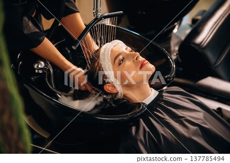 Lying down, washing the hair. Woman is in a beauty salon with hair stylist 137785494