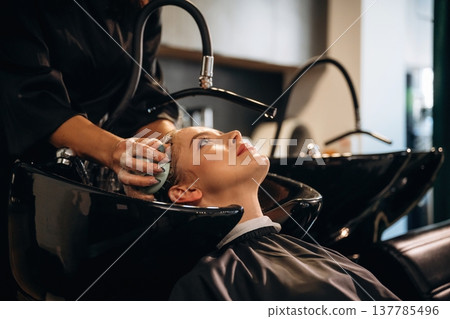 Massaging the skin on head. Woman is in a beauty salon with hair stylist 137785496