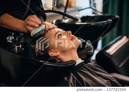 Healthy massage for the head and skin. Woman is in a beauty salon with hair stylist Healthy massage for the head and skin. Woman is in a beauty salon with hair stylist 137785504