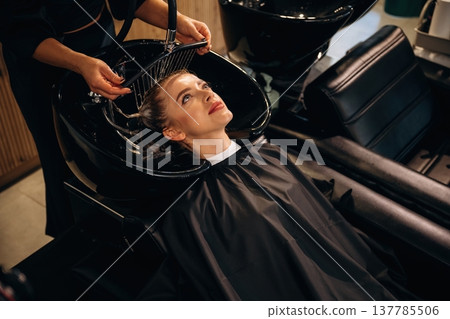 Clean water, washing hair. Woman is in a beauty salon with hair stylist Clean water, washing hair. Woman is in a beauty salon with hair stylist 137785506