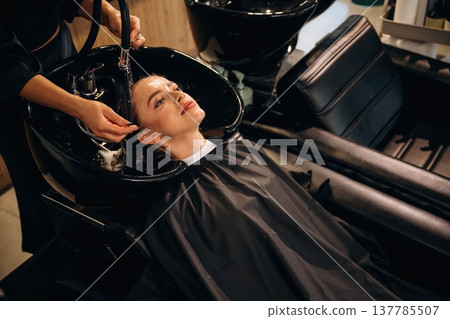 Clean water, washing hair. Woman is in a beauty salon with hair stylist Clean water, washing hair. Woman is in a beauty salon with hair stylist 137785507