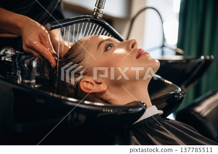 Service for customer, washing head. Woman is in a beauty salon with hair stylist Service for customer, washing head. Woman is in a beauty salon with hair stylist 137785511