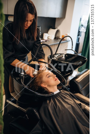 Deep cleaning, washing. Woman is in a beauty salon with hair stylist Deep cleaning, washing. Woman is in a beauty salon with hair stylist 137785515