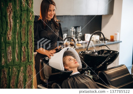 Using the LED hair growth helmet. Woman is in a beauty salon with hair stylist Using the LED hair growth helmet. Woman is in a beauty salon with hair stylist 137785522