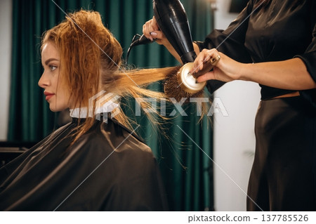 Drying the hair. Woman is in a beauty salon with hair stylist Drying the hair. Woman is in a beauty salon with hair stylist 137785526
