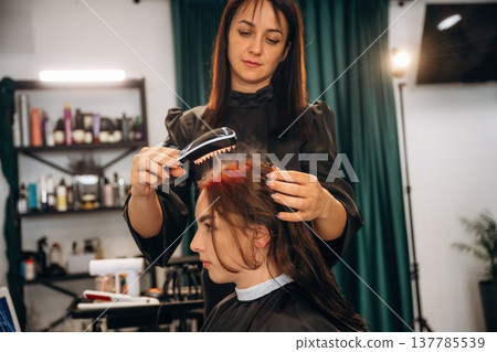 Woman is in a beauty salon with hair stylist Woman is in a beauty salon with hair stylist 137785539