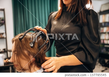 Pleasant massage for head. Woman is in a beauty salon with hair stylist Pleasant massage for head. Woman is in a beauty salon with hair stylist 137785545