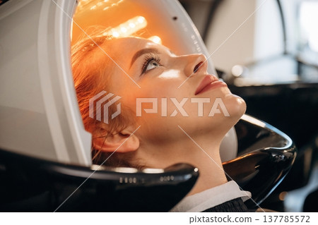 Yellow color. Woman is in a beauty salon with LED hair growth helmet Yellow color. Woman is in a beauty salon with LED hair growth helmet 137785572