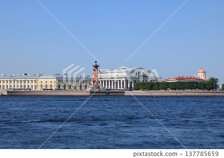 Russia, Petersburg, June 8, 2019. Spit of Vasilyevsky Island. Pictured is the Rostral Column and the Stock Exchange building on the bank of the Neva on the background of the summer sky 137785659